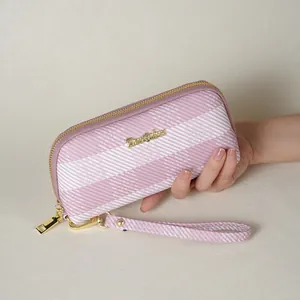 Primo piano di una mano che tiene una pochette a righe rosa e bianche con cinturino