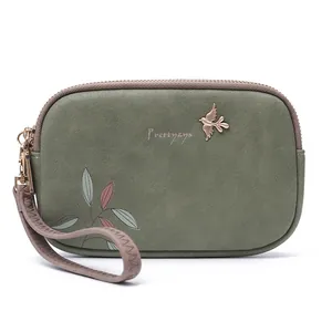 Detail of green double zipper clutch bag with bird emblem and floral leaf print design