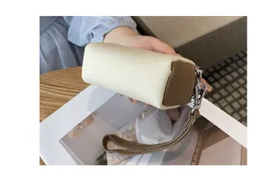 Dettaglio della pochette da polso in pelle martellata crema e marrone con cerniere