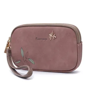 Detailed macro view of a dusty rose double zipper wristlet wallet featuring elegant leaf print
