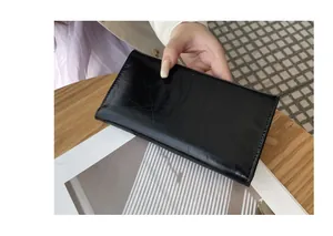 Vista detallada de una cartera larga negra ultra fina de moda con textura de cuero craquelado.