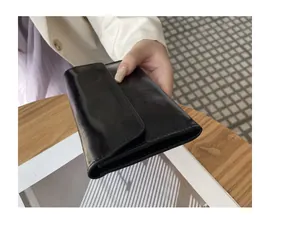 Vista detallada de una elegante cartera larga de cuero negro con textura agrietada