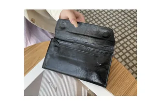 Detalle que muestra la textura agrietada y las ranuras para tarjetas de esta cartera larga negra