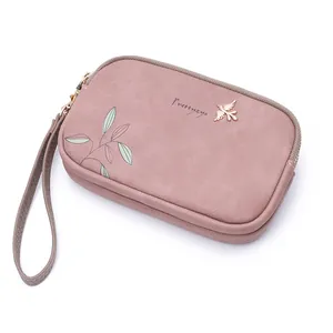 Detailed view of dusty pink double zipper clutch with elegant floral print and wristlet