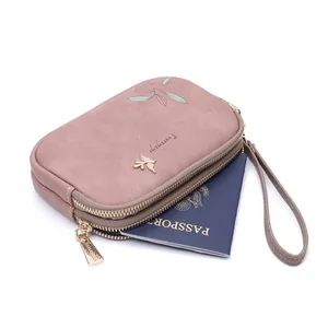 Detail view of pink double-zippered wristlet showing passport storage for travel