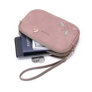 Detail of pink double zipper clutch bag showing capacity for phone, passport and cash