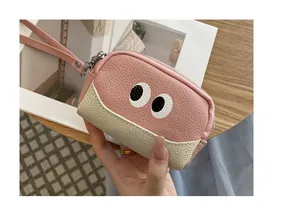 Dettaglio del portamonete in pelle rosa e beige con design a occhi di cartone animato
