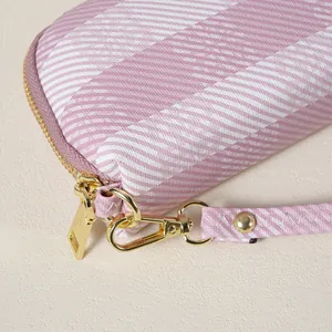 Dettaglio della cerniera dorata e della ferramenta sulla pochette a righe rosa