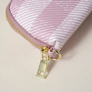 Dettaglio ravvicinato della cerniera in metallo dorato su pochette da donna a righe rosa