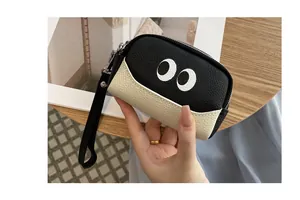 Dettaglio di un portamonete in pelle con occhi a cartone animato e cinturino nero.