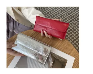 Vista detallada de carteras largas rojas y plateadas con textura de cuero agrietado