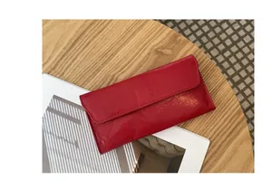 Primer plano de cartera larga de cuero rojo con textura arrugada única en mesa.