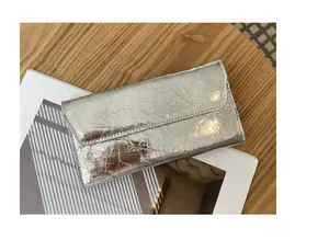 Primer plano de una cartera larga plateada para mujer con textura de cuero agrietado.