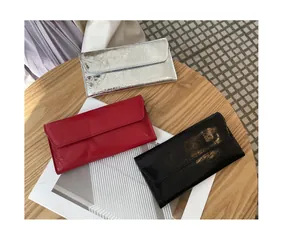 Vista detallada de tres carteras largas para mujer en plata, rojo y negro con efecto craquelado