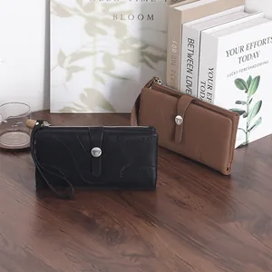 Zwei elegante lange Kunstlederbrieftaschen in Schwarz und Braun auf einem Holzschreibtisch