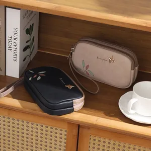 Detail of dual-zipper women's wallets in black and beige with leaf prints and bird logo