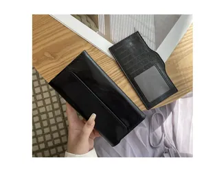 Primer plano de una cartera larga de cuero negro con textura agrietada y tarjetero.
