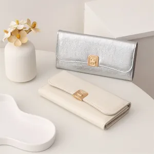 Close-up of elegant long wallets in silver and cream with crinkled texture and gold clasp