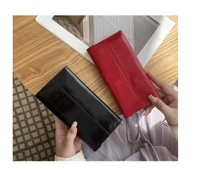 Primer plano de carteras largas en negro y rojo con textura agrietada y cierre magnético