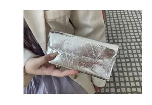 Primer plano de una cartera larga de cuero plateado con patrón agrietado y solapa.
