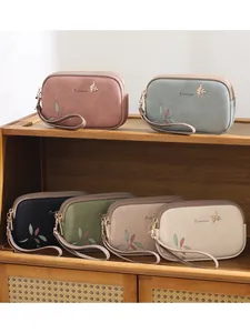 Fashionable double-zipper wristlet bag for women with leaf print and bird charm.