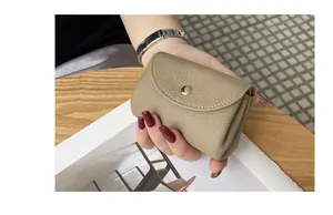 Detailed view of a compact khaki genuine leather coin purse held in hand for scale