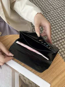 Elegante cartera larga de mujer en cuero negro con textura agrietada y cierre magnético