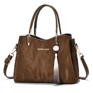 Elegant brown textured handbag with floral tassel charm for women's stylish daily commute.