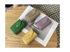Close-up of four colorful pebbled leather mini coin purses with gold snap closures on a table