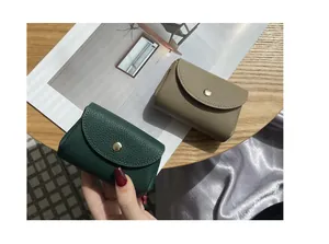 Close-up top view of two pebbled leather mini wallets in green and taupe tones