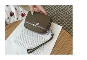 Detail of olive green pebbled leather mini pouch with double zippers and wrist strap