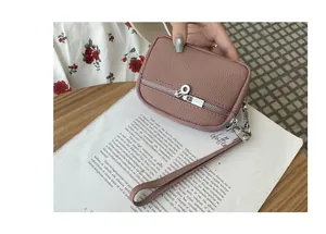 Close-up of dusty pink mini coin purse with double zippers and wristlet strap.