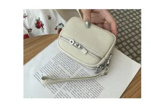 Detail of a stylish cream-white mini coin purse featuring double zippers and wrist strap