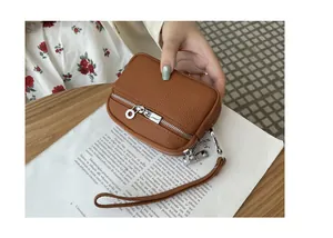Close-up of a brown double-zipper coin purse held over a magazine on a wooden table