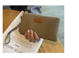 Detailed view of the textured leather clutch with wristlet and gold zipper.