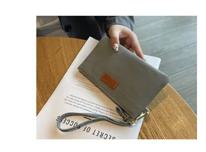 Close-up of elegant gray pebbled leather pouch with wrist strap and secure gold zipper closure