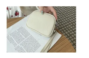 Close-up of a cream pebbled leather mini coin purse with double zippers and wristlet strap.