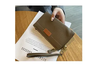 Close-up of a small pebbled leather wristlet pouch in brown with a gold zipper detail