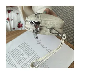 Close-up of beige double-zip coin purse with pebbled leather texture.