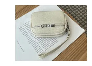 Close-up detail of a cream textured leather coin purse with double silver zippers