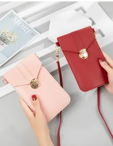 Detailed view of pink and red crossbody phone bags with gold latches held by hands.