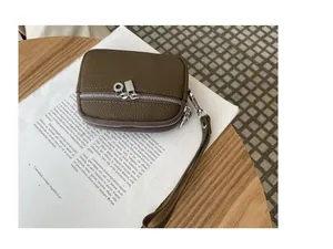 Close-up of olive green double zipper coin pouch with wrist strap on a lifestyle background