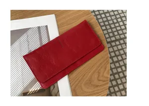 Gedetailleerde close-up van een slanke rode zachte leren damesportemonnee op tafel