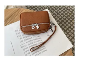Close-up of tan pebbled leather mini coin purse with double silver zippers and strap.