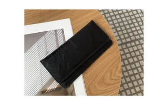 Gedetailleerd beeld van de glanzende afwerking van een slanke zwarte leren damesportemonnee