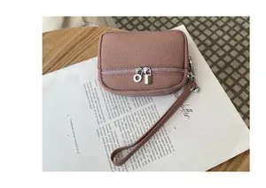 Close-up detail of a pink mini coin pouch featuring double zippers and a handy wristlet strap