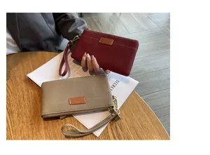Detailed view of elegant red and khaki pebbled leather clutch bags on a cafe wooden table.