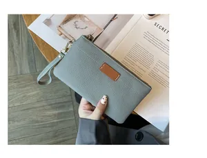 Close-up detail of a minimalist gray pebbled leather clutch bag held over an open magazine