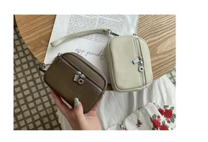 Close-up of stylish mini leather coin purses featuring double zippers and carry straps