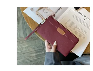 Close-up detail of burgundy genuine leather wristlet with elegant white stitching and texture.